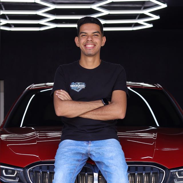 Guilherme, do Guizera Studio, apoiado num carro no estúdio